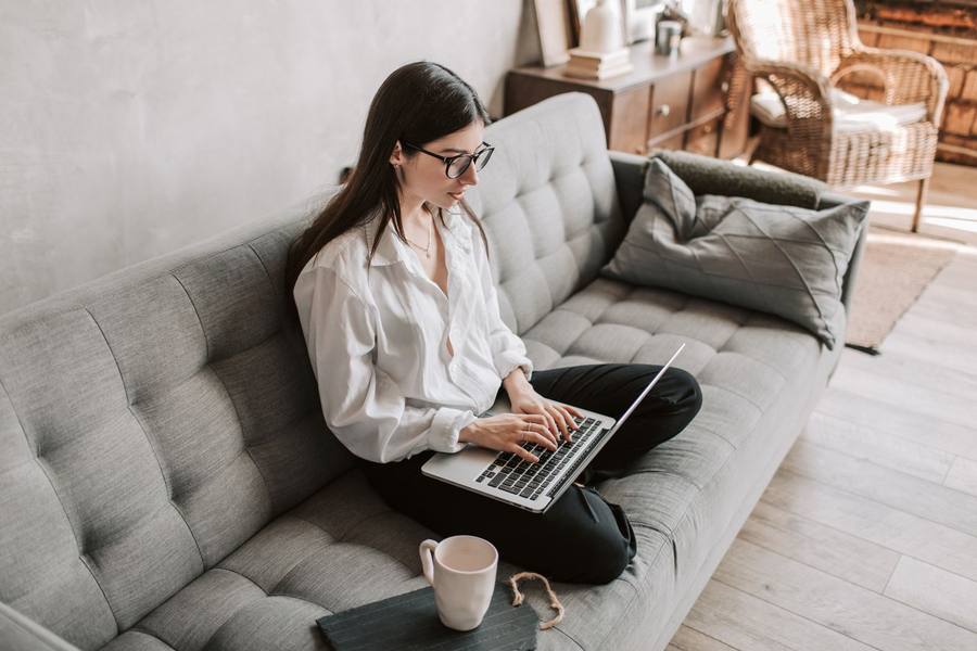 Woman sitting on a sofa searching for jobs on her laptop